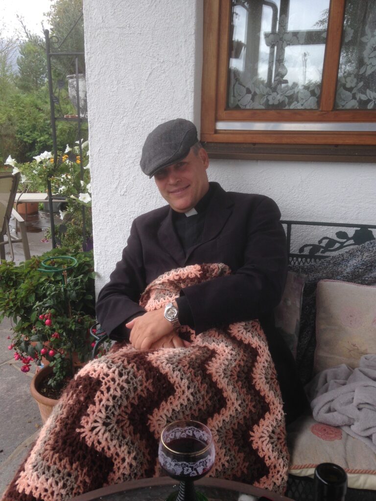 A Person Sitting on a Bench With a Blanket Over Their Lap and a Drink on the Table in Front of Them